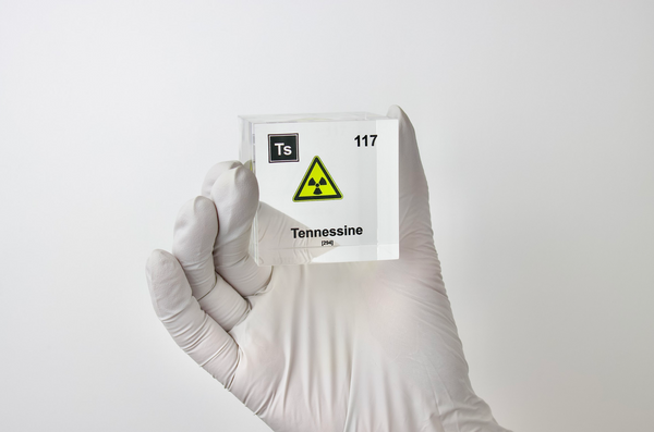 Clear acrylic cube displaying a Tennessine element (Atomic Number 117) embedded within, offering a scientific presentation for collectors and science enthusiasts.