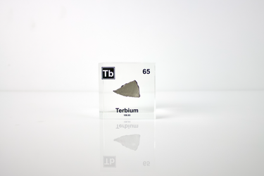 Clear acrylic cube displaying a Terbium element (Atomic Number 65) embedded within, offering a scientific presentation for collectors and science enthusiasts.