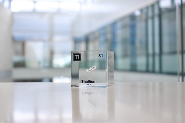 Clear acrylic cube displaying a Thallium element (Atomic Number 81) embedded within, offering a scientific presentation for collectors and science enthusiasts.