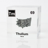 Clear acrylic cube displaying a Thulium element (Atomic Number 69) embedded within, offering a scientific presentation for collectors and science enthusiasts.