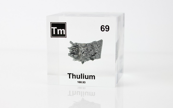 Clear acrylic cube displaying a Thulium element (Atomic Number 69) embedded within, offering a scientific presentation for collectors and science enthusiasts.