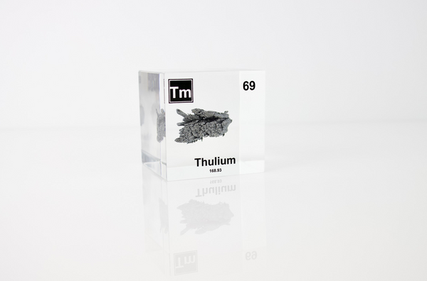 Clear acrylic cube displaying a Thulium element (Atomic Number 69) embedded within, offering a scientific presentation for collectors and science enthusiasts.