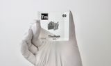 Clear acrylic cube displaying a Thulium element (Atomic Number 69) embedded within, offering a scientific presentation for collectors and science enthusiasts.