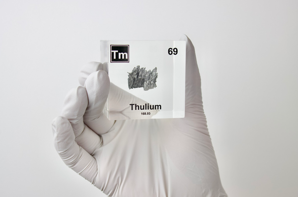 Clear acrylic cube displaying a Thulium element (Atomic Number 69) embedded within, offering a scientific presentation for collectors and science enthusiasts.