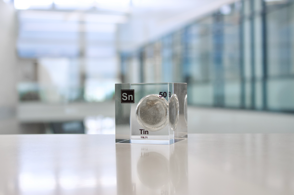 Clear acrylic cube displaying a Tin element (Atomic Number 50) embedded within, offering a scientific presentation for collectors and science enthusiasts.