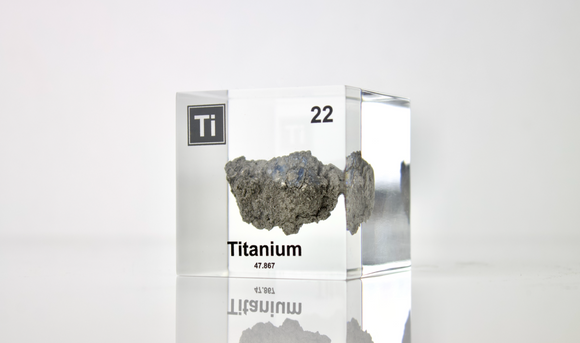 Clear acrylic cube displaying a Titanium element (Atomic Number 22) embedded within, offering a scientific presentation for collectors and science enthusiasts.