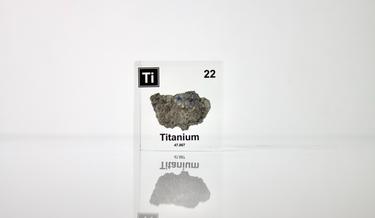 Clear acrylic cube displaying a Titanium element (Atomic Number 22) embedded within, offering a scientific presentation for collectors and science enthusiasts.