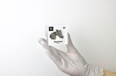 Clear acrylic cube displaying a Titanium element (Atomic Number 22) embedded within, offering a scientific presentation for collectors and science enthusiasts.