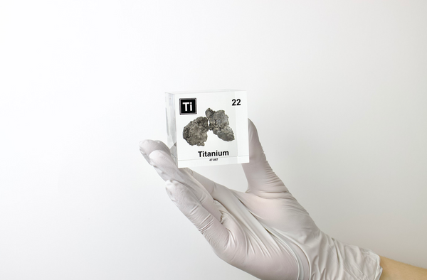 Clear acrylic cube displaying a Titanium element (Atomic Number 22) embedded within, offering a scientific presentation for collectors and science enthusiasts.