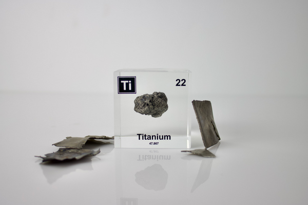 Clear acrylic cube displaying a Titanium element (Atomic Number 22) embedded within, offering a scientific presentation for collectors and science enthusiasts.