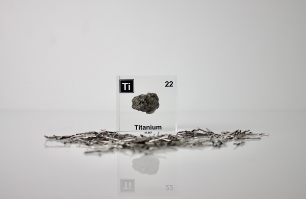 Clear acrylic cube displaying a Titanium element (Atomic Number 22) embedded within, offering a scientific presentation for collectors and science enthusiasts.