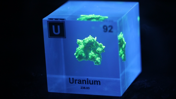 Uranium element cube with element glowing from exposure to black light.