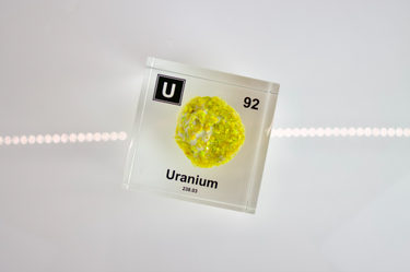 Clear acrylic cube showcasing a Uranium element (Atomic Number 92) embedded within, offering a scientific display for collectors and science enthusiasts.