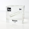 Clear acrylic cube displaying a Xenon element (Atomic Number 54) embedded within, offering a scientific presentation for collectors and science enthusiasts.