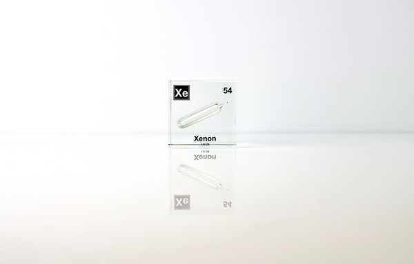 Clear acrylic cube displaying a Xenon element (Atomic Number 54) embedded within, offering a scientific presentation for collectors and science enthusiasts.