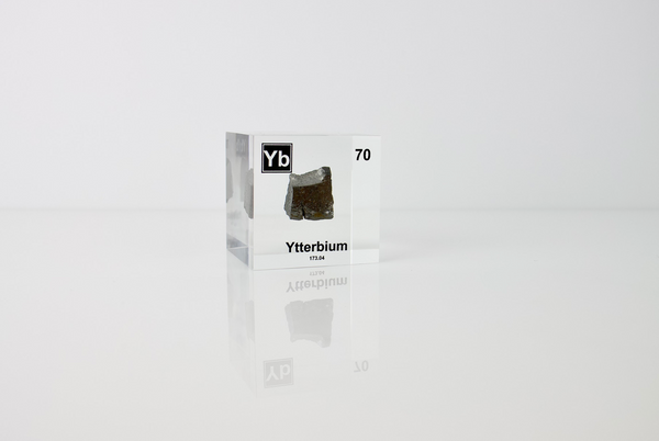 Clear acrylic cube displaying an Ytterbium element (Atomic Number 70) embedded within, offering a scientific presentation for collectors and science enthusiasts.