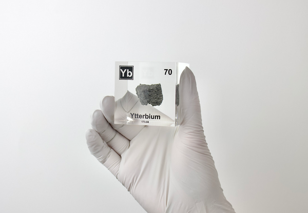 Clear acrylic cube displaying an Ytterbium element (Atomic Number 70) embedded within, offering a scientific presentation for collectors and science enthusiasts.