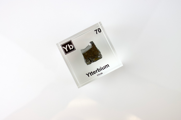 Clear acrylic cube displaying an Ytterbium element (Atomic Number 70) embedded within, offering a scientific presentation for collectors and science enthusiasts.