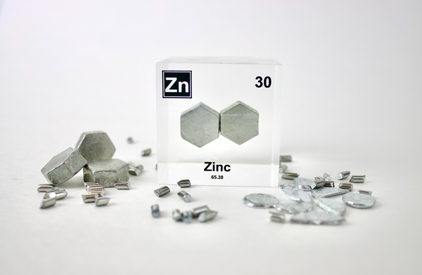 Zinc element encased in a clear acrylic cube, surrounded by its raw element, featuring its name, atomic number 30, and properties as displayed on the periodic table. Ideal for educational and collector use.