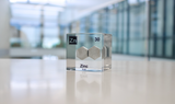 Zinc element encased in a clear acrylic cube, featuring its name, atomic number 30, and properties as displayed on the periodic table. Ideal for educational and collector use.