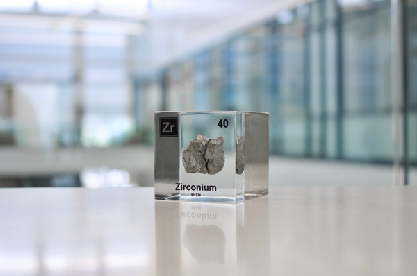 Clear acrylic cube displaying a Zirconium element (Atomic Number 40) embedded within, offering a scientific presentation for collectors and science enthusiasts.