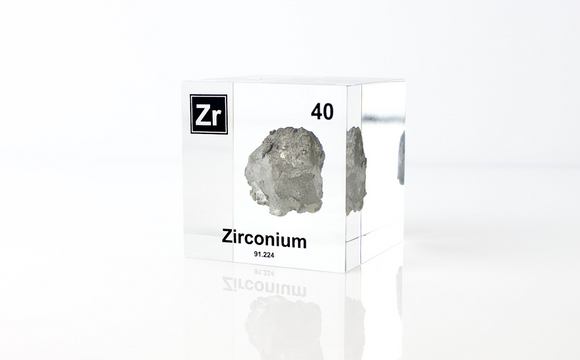 Clear acrylic cube displaying a Zirconium element (Atomic Number 40) embedded within, offering a scientific presentation for collectors and science enthusiasts.