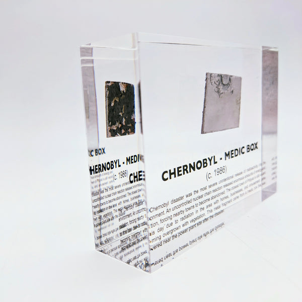 Clear acrylic display case featuring a historical fragment of a Chernobyl medic box, offering an educational presentation for collectors and those interested in nuclear history.